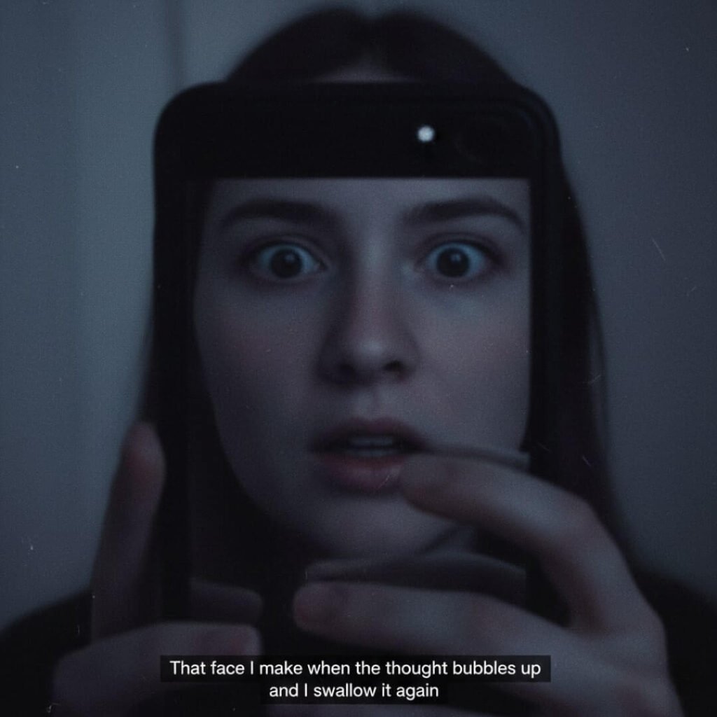 Reflection in dark phone screen, wide eyes, half-open mouth.