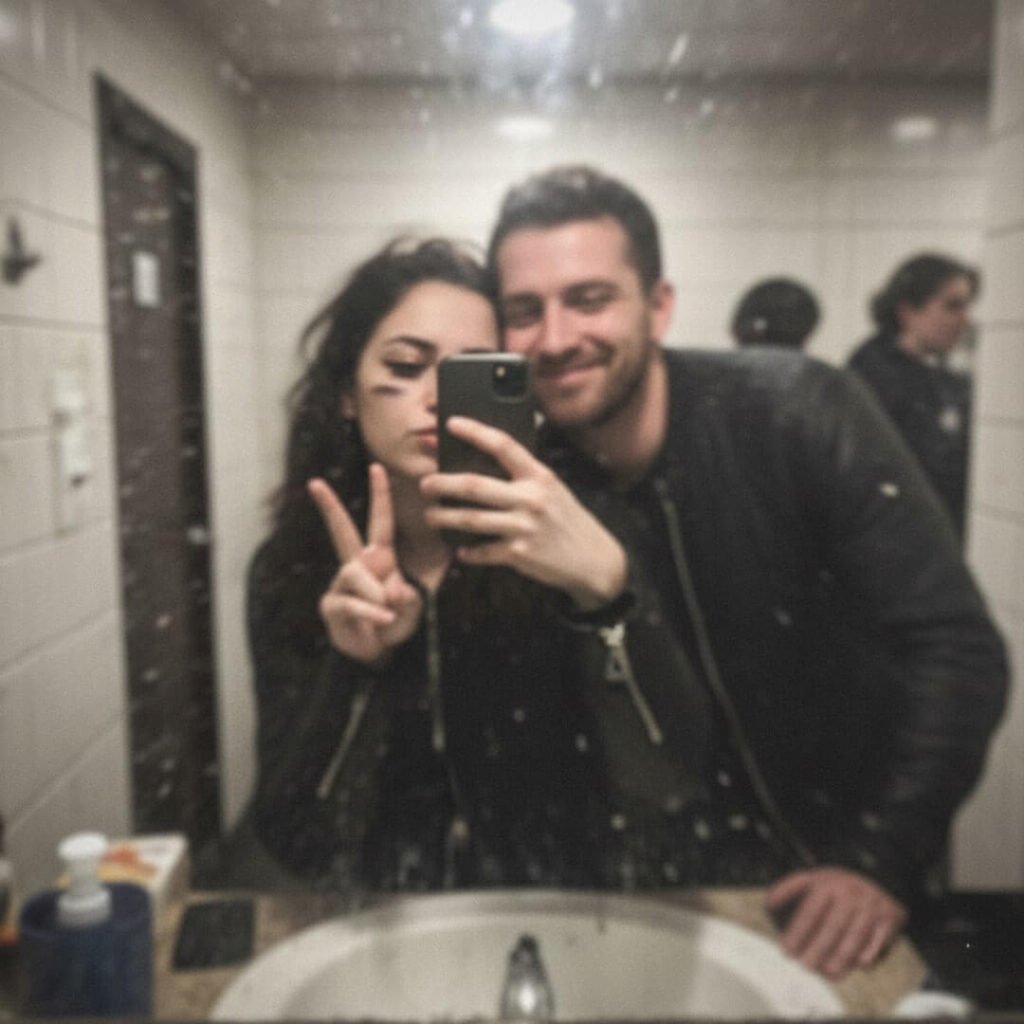 Blurry bar-bathroom mirror selfie with smudged eyeliner and goofy grin.